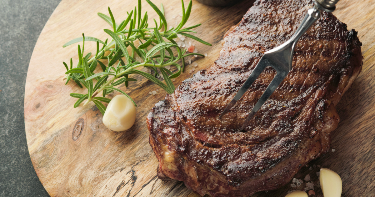 A perfectly seared prime steak served on a wooden board with rosemary and garlic, representing the high-quality dining found at five star restaurants in Charlotte NC.