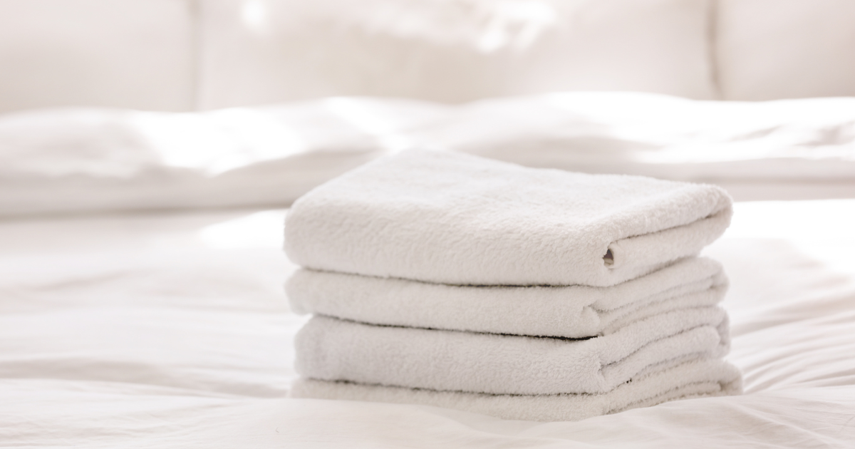 outsource laundry - The WashRoom Laundry Service A stack of fresh, bright white towels demonstrating the high-quality results when businesses outsource laundry.