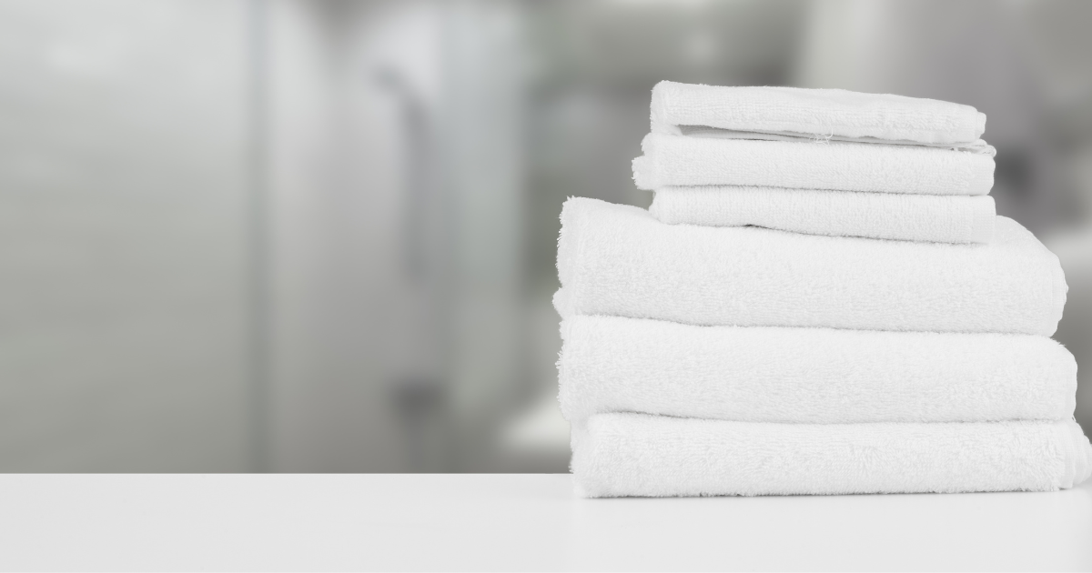 commercial laundry services - The WashRoom Laundry Service A perfectly folded stack of fresh, clean white towels, representing the consistent quality and hygiene achieved with commercial laundry services for businesses like hotels, spas, and fitness centers.