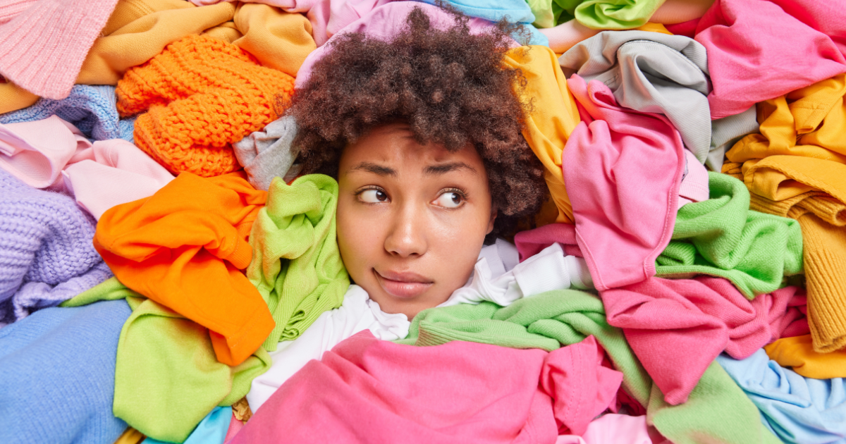 Woman overwhelmed by a mountain of laundry, illustrating why a wash and fold laundry service saves time and stress