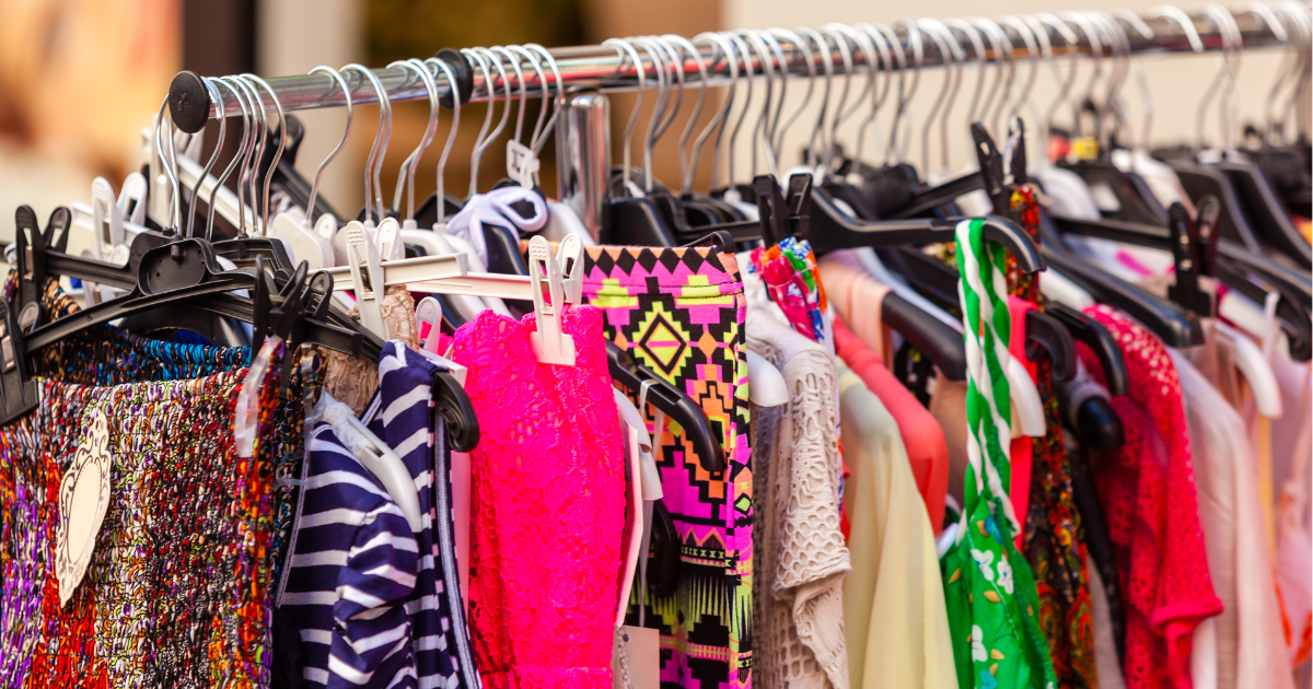 A rack of colorful new clothes with tags still attached, prompting the question: should you wash new clothes before wearing them?