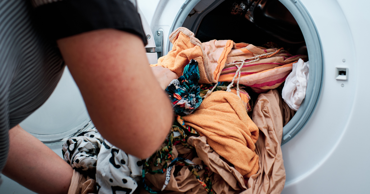should you wash new clothes - The WashRoom Laundry Service A person loading new clothes into a washing machine for a pre-wash cycle, emphasizing proper garment care and hygiene.