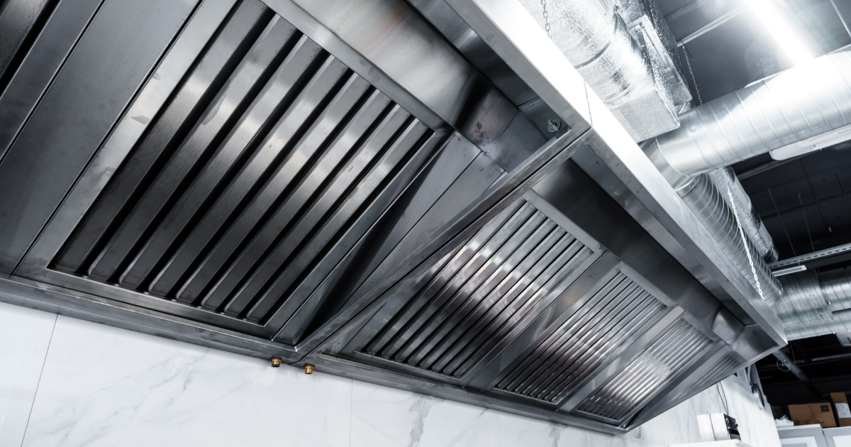 Stainless steel commercial kitchen exhaust hood with baffle filters and ductwork after restaurant hood cleaning