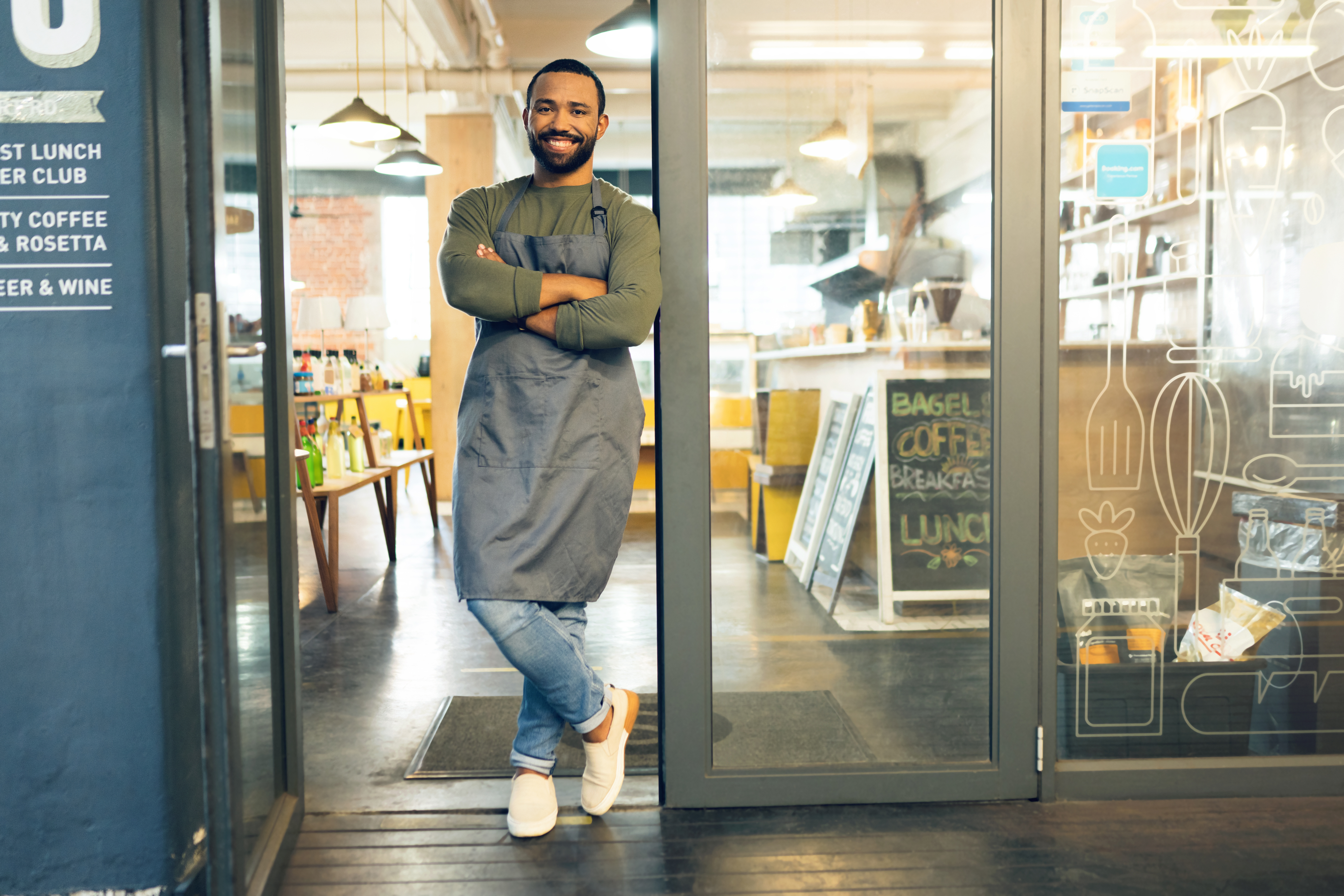 Restaurant owner standing at entrance with commercial entry mat visible in doorway