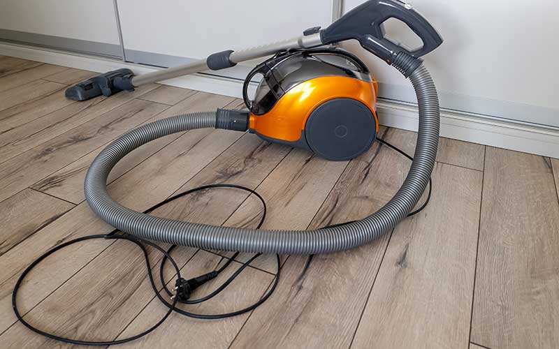 clean a dryer vent duct - The WashRoom Laundry Service A vacuum cleaner with a hose attachment being prepared to clean out dryer exhaust and lint from a home vent system.